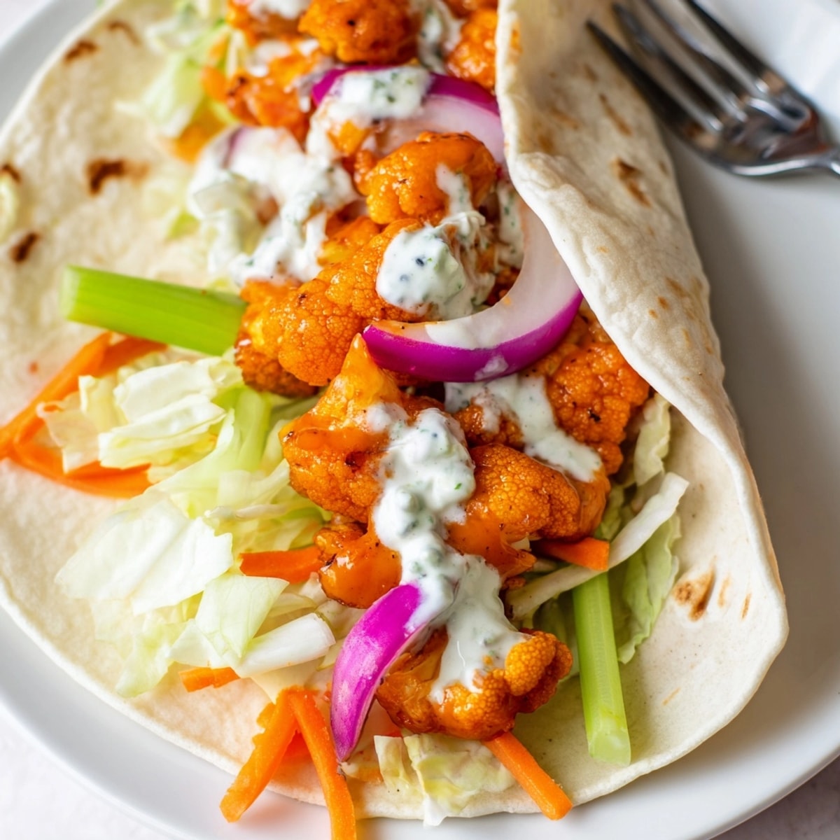 Golden Buffalo Cauliflower Wraps filled with veggies and creamy dressing, ready to enjoy.