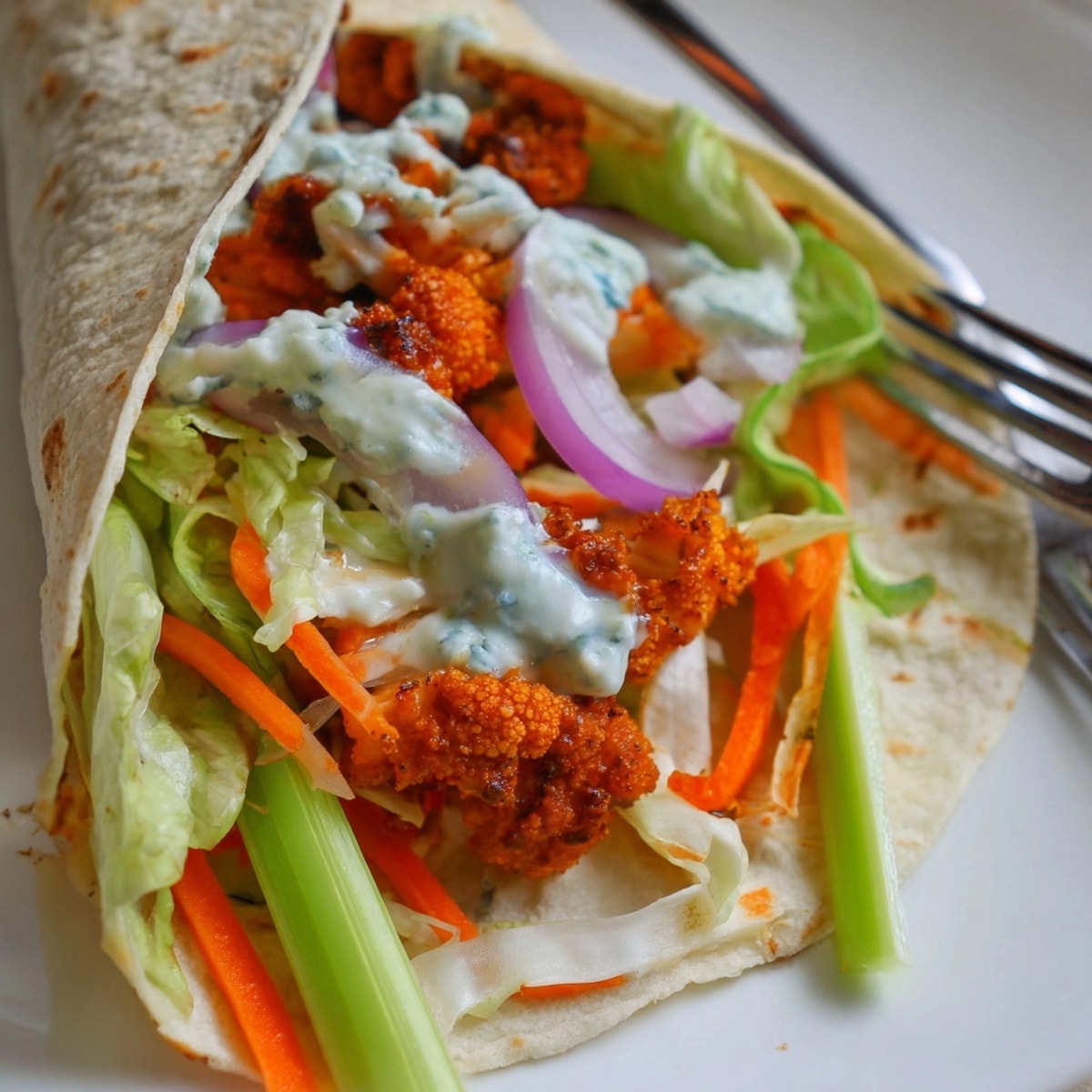 Close-up of a Buffalo Cauliflower Wrap; spicy, tangy, and irresistible, ideal for game day.