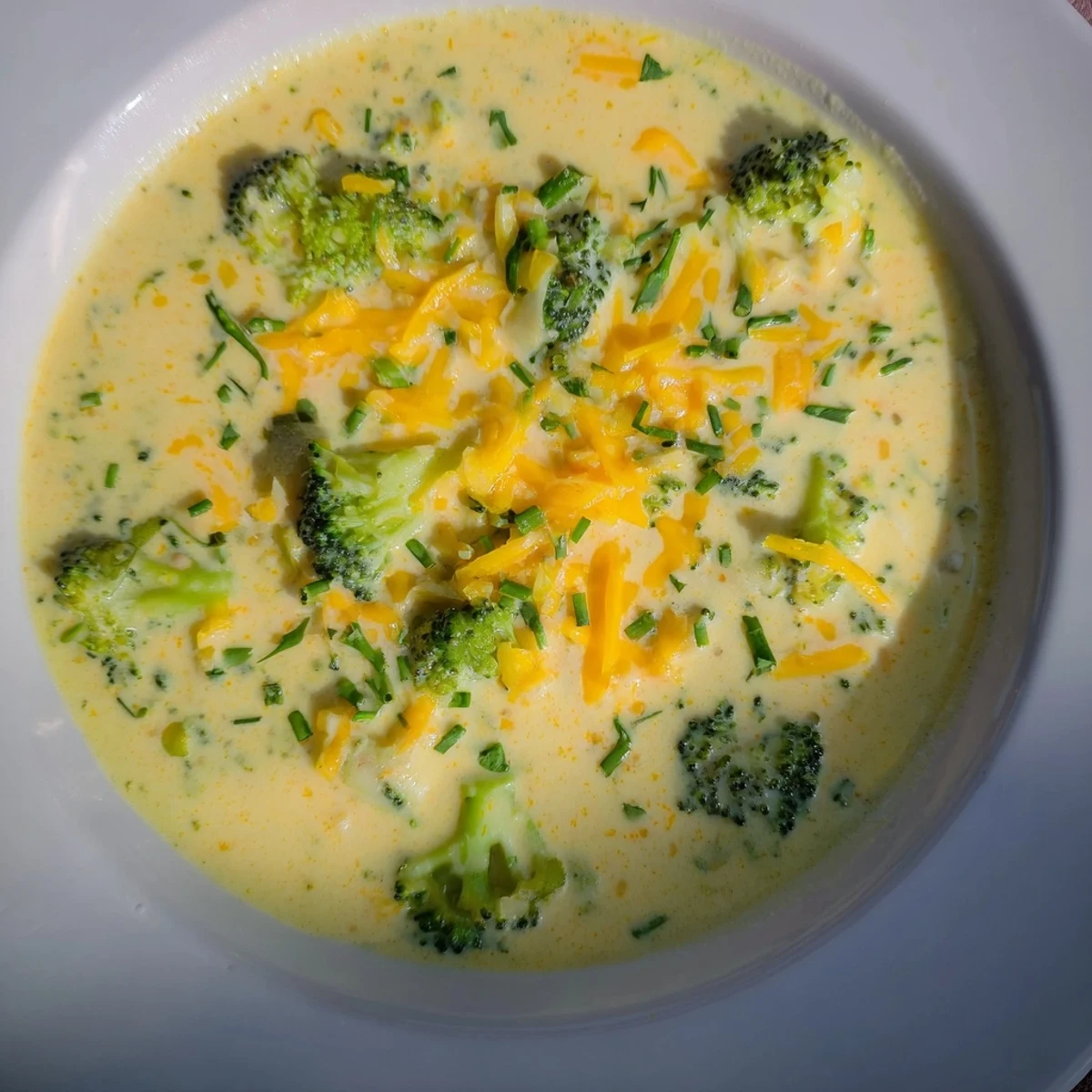 A steaming bowl of creamy Broccoli Cheddar Soup, garnished with fresh chives, ready to enjoy.