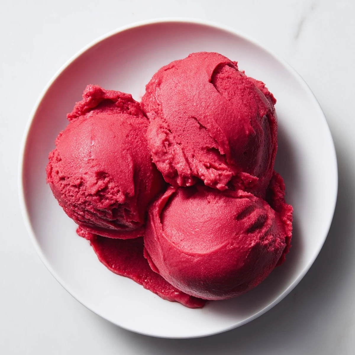 Vibrant red Cranberry Sorbet, a refreshing dessert, scooped into a clear glass, ready to eat.