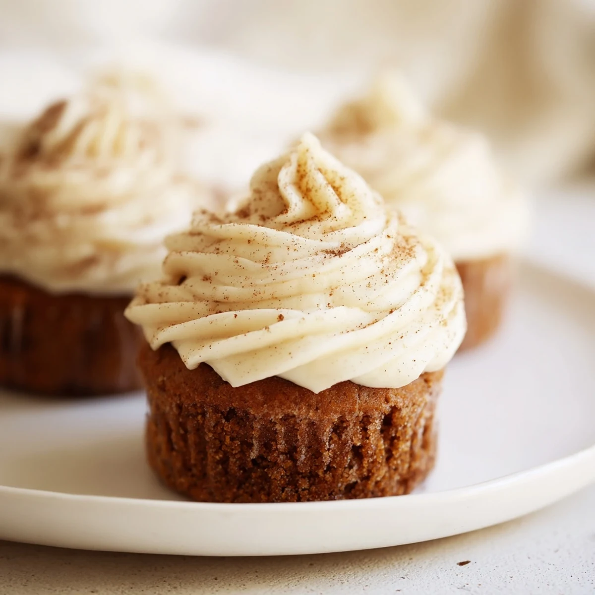 Fluffy gingerbread cupcakes sit frosted with creamy vanilla, ready for a festive dessert.