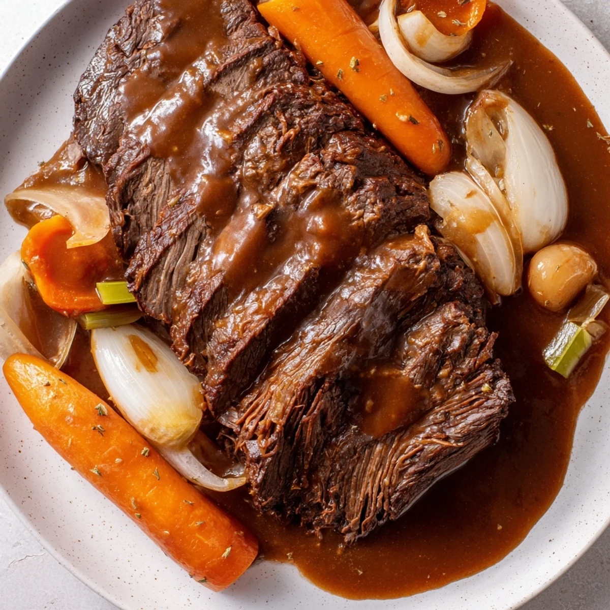 Slices of tender, fall-apart braised steak, glistening with rich gravy, ready for a comforting meal.
