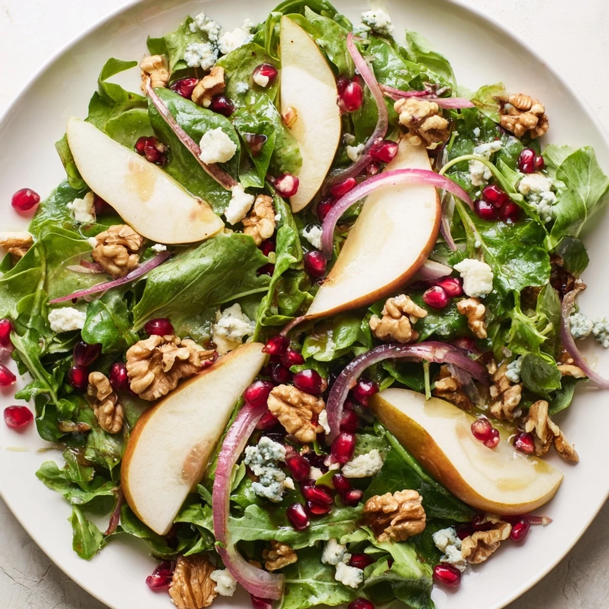 A refreshing Winter Green Salad with pears, walnuts, and tangy dressing, ready to enjoy.