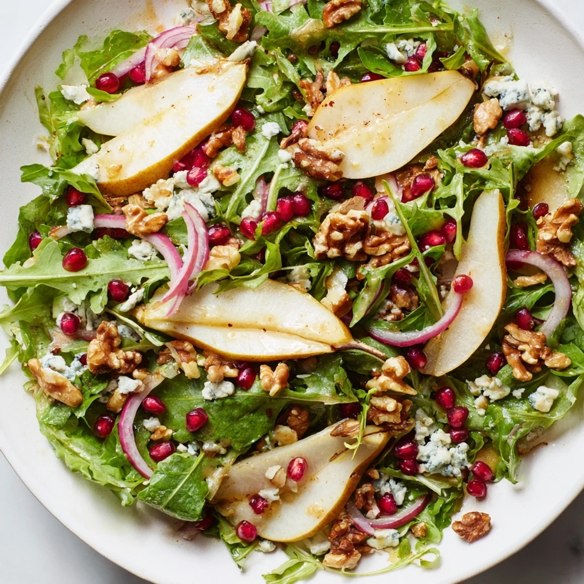 Bright green Winter Green Salad with pear slices and toasted walnuts in a light vinaigrette.