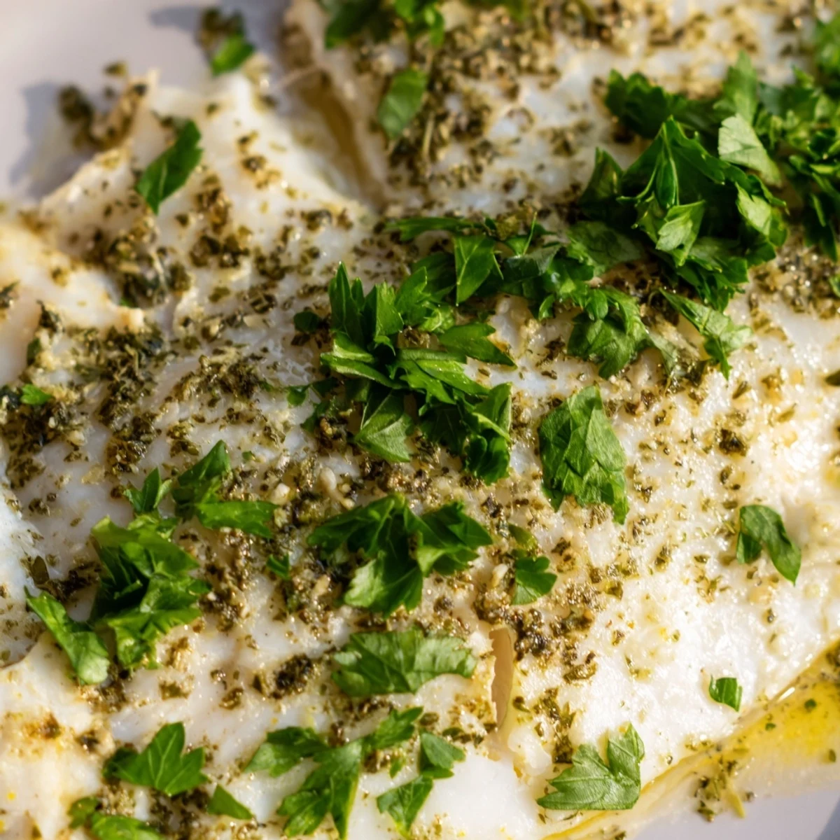Flaky and tender Baked Tilapia fillets seasoned with garlic and herbs on a baking sheet, steaming hot.