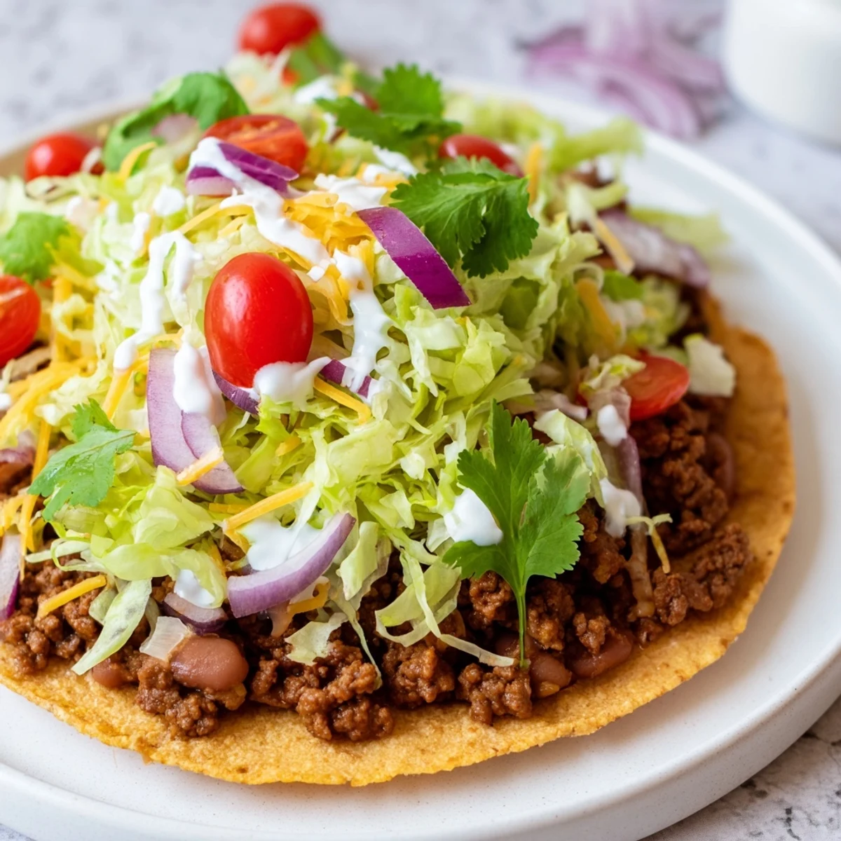 Crispy corn tostada shells layered with creamy refried beans and seasoned ground beef, topped with fresh lettuce, tomatoes, and cheese.