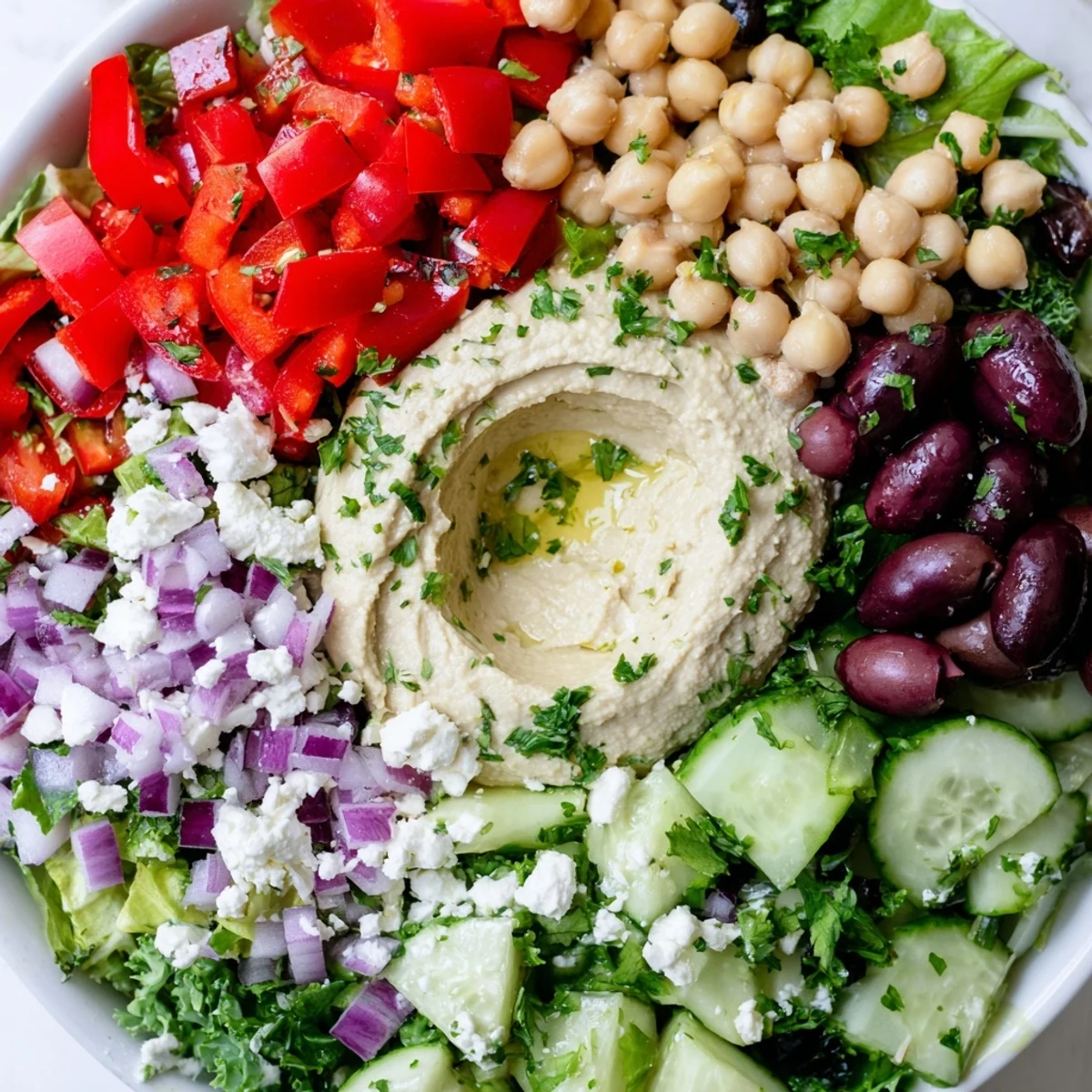 Bright bowl of Mediterranean Salad with Hummus, featuring crumbled feta, Kalamata olives, and a lemony dressing for lunch.