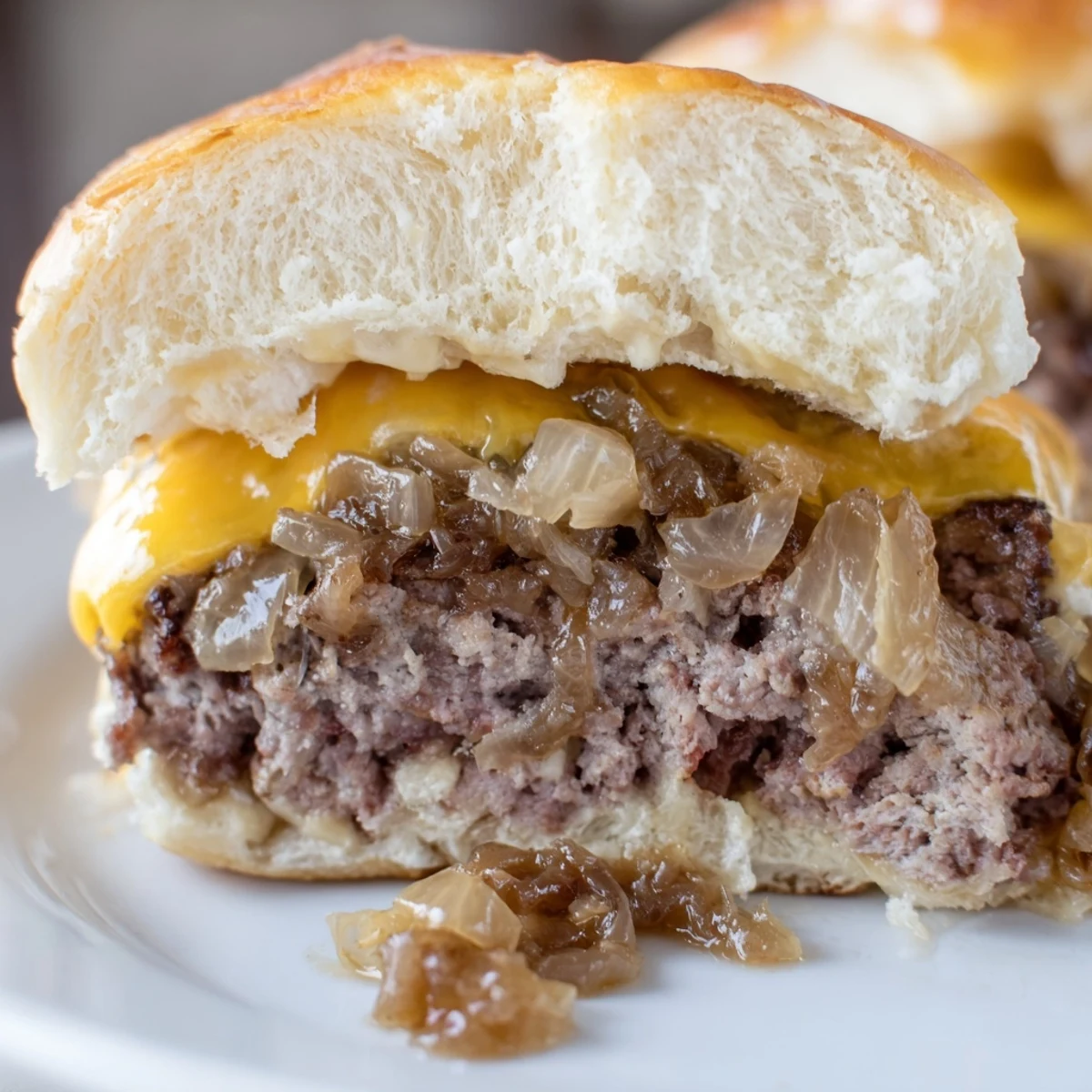 Golden-brown Beef Sliders with Caramelized Onions and Cheese featuring melted cheddar on juicy mini burgers.
