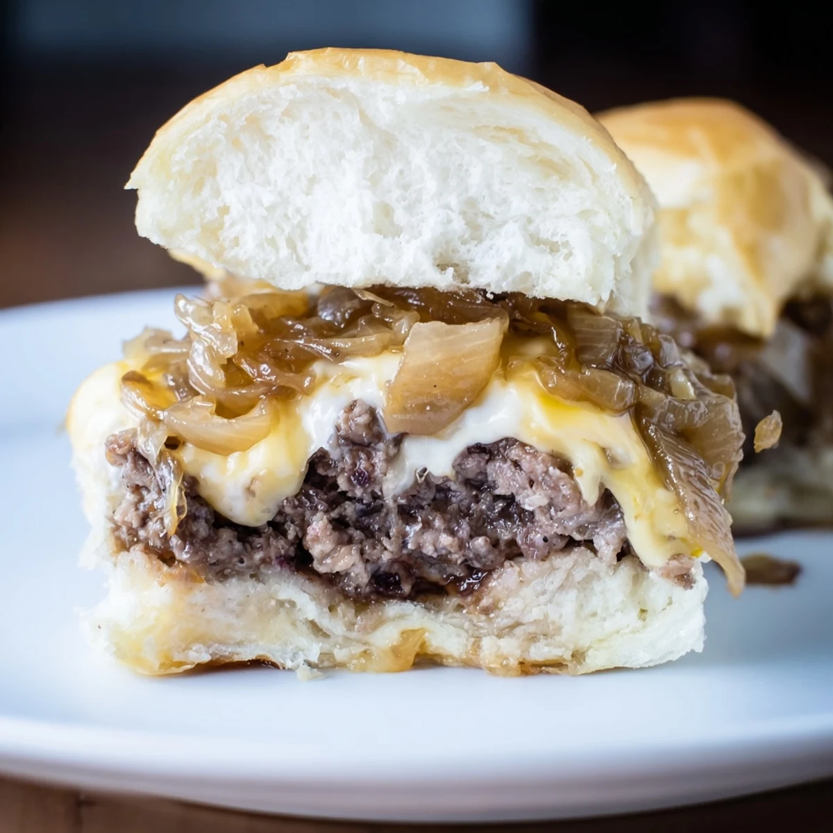 Close-up of Beef Sliders with Caramelized Onions and Cheese topped with sweet, jammy onions and cheese.