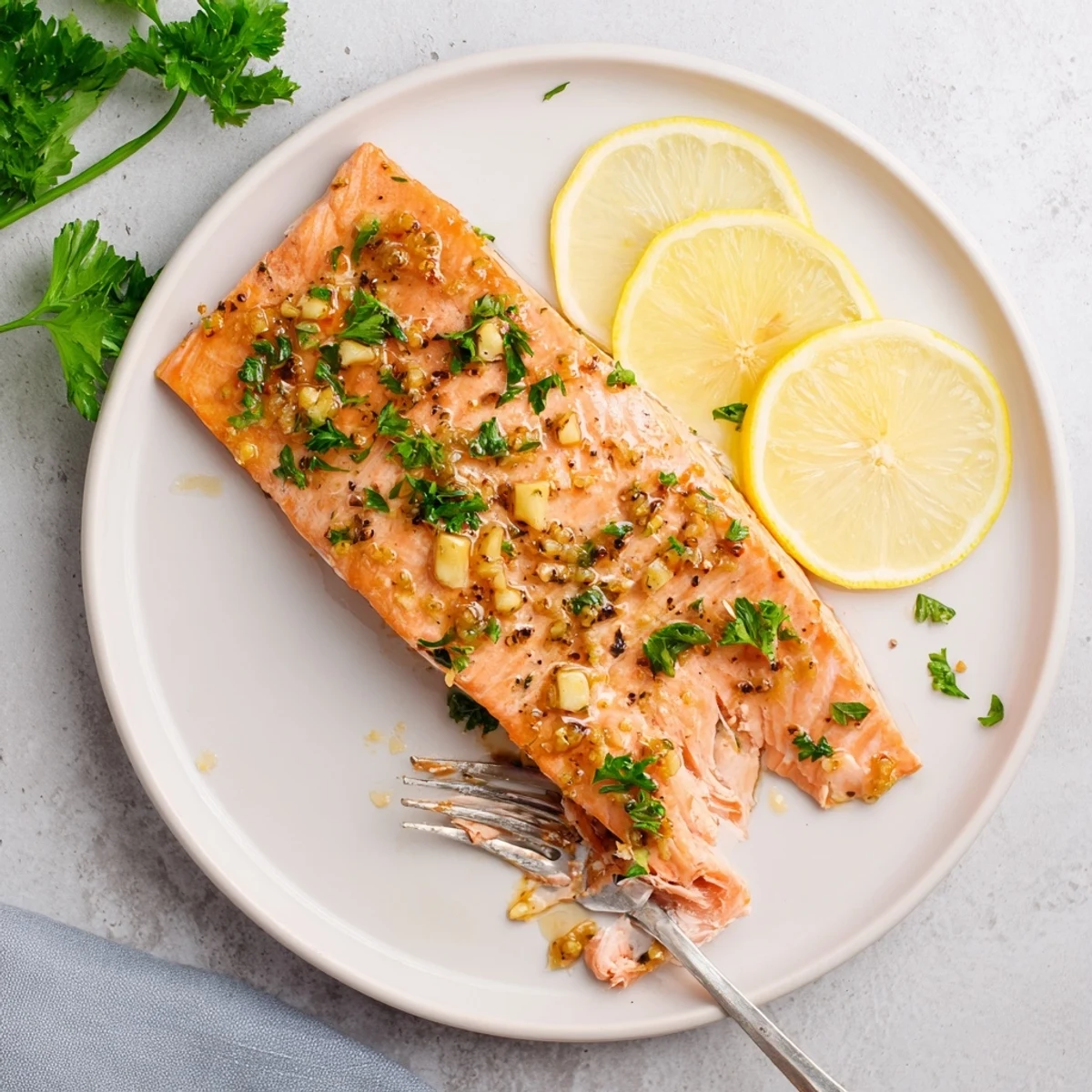 A close-up of tender, flaky Baked Salmon with Honey Garlic Glaze, garnished with fresh parsley and served with lemon wedges.