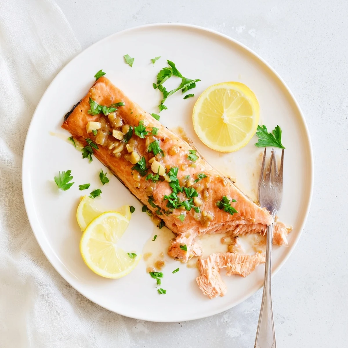 Moist, oven-baked salmon fillets with a sticky honey garlic glaze, paired with steamed vegetables on a white dinner plate.