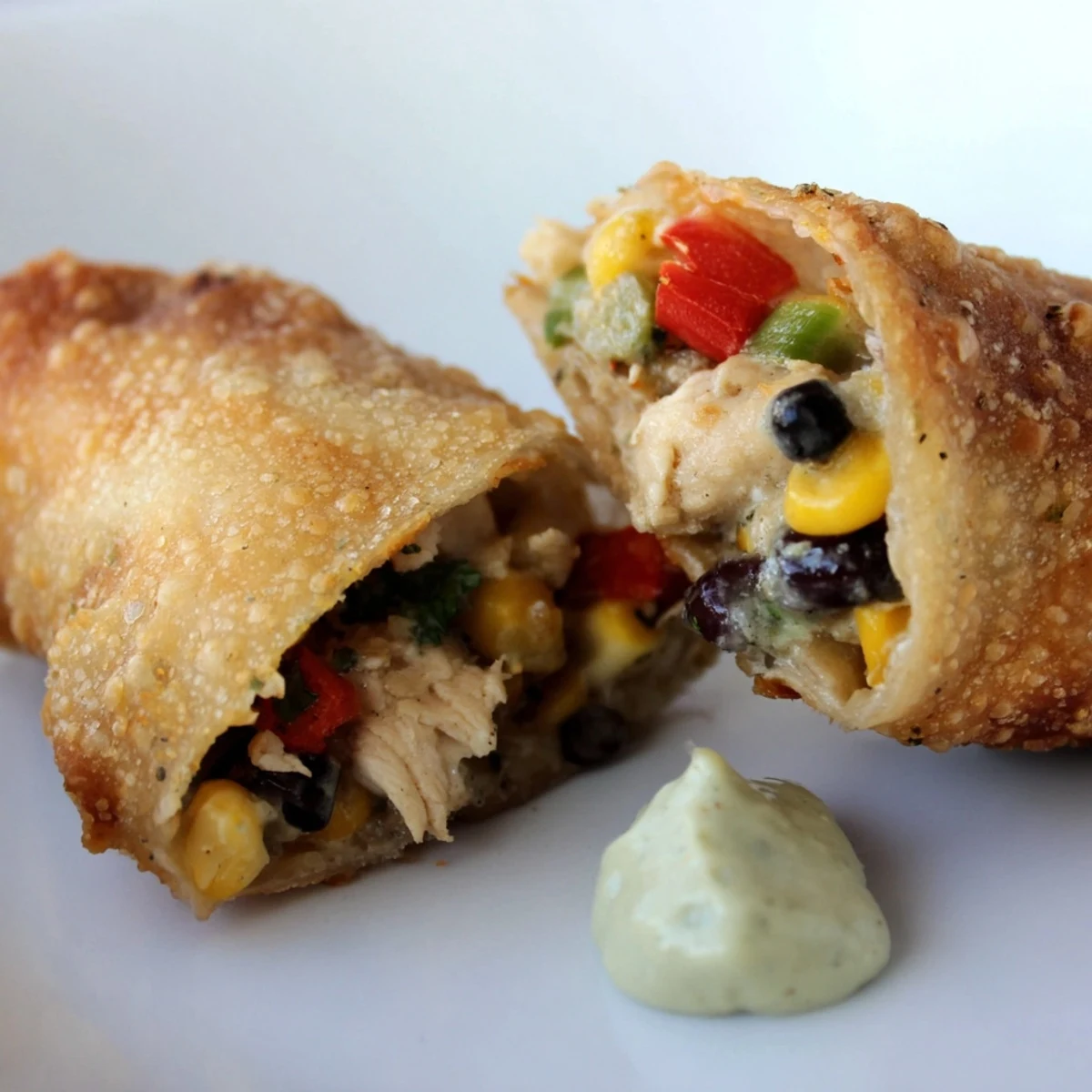 Golden brown Southwest egg rolls on a platter, served with creamy avocado ranch dip for a Super Bowl party.