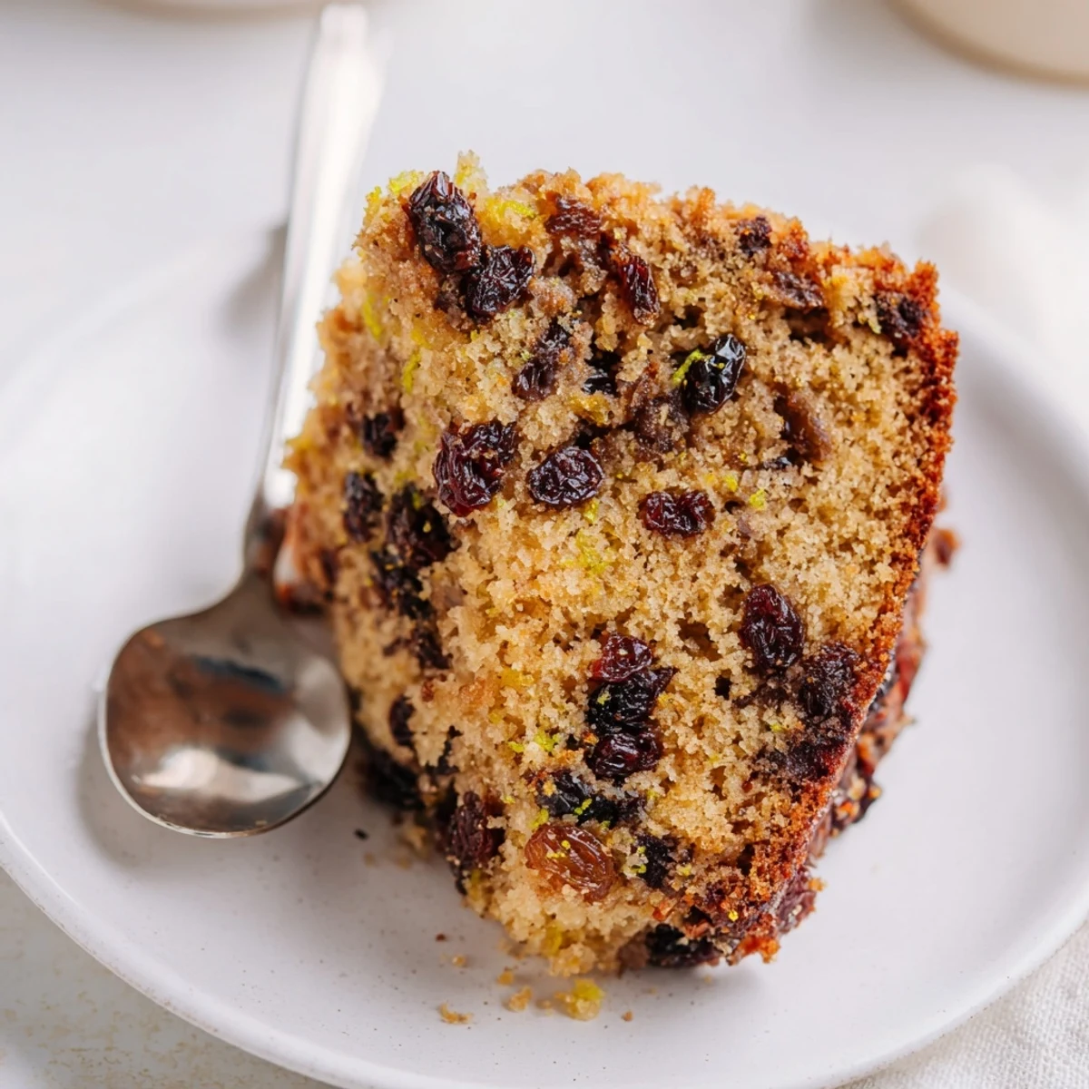 Irish Tea Cake with Dried Fruit cut into a thick wedge, revealing a tender interior studded with soaked fruit, ideal for an afternoon snack.