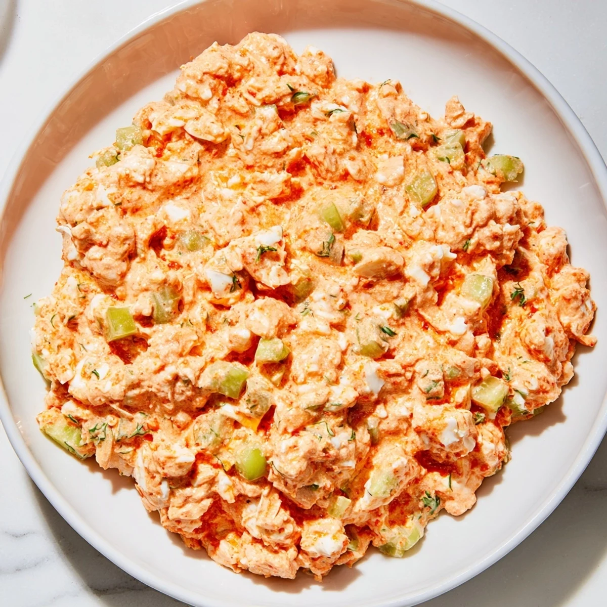 Hearty Cajun Remoulade Sauce with Crab served in a white dish, garnished with fresh herbs and lemon wedges.  