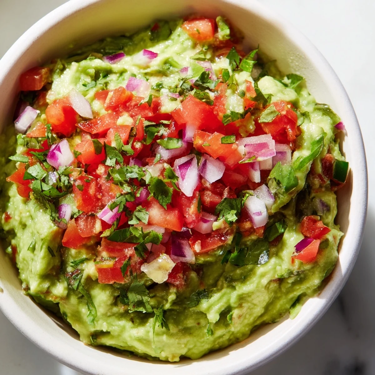Creamy Super Bowl Guacamole with Pico de Gallo served in a rustic bowl, ready to scoop with crispy golden tortilla chips for game day.