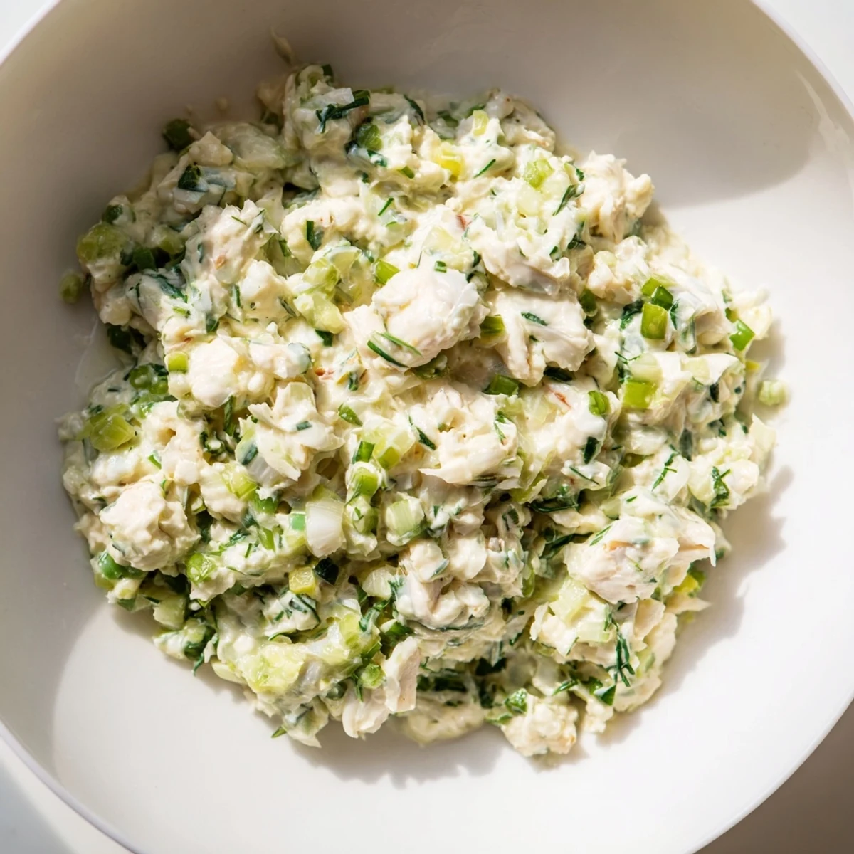 In a white dish, Remoulade Sauce with Crab Meat is garnished with chopped celery and scallions, ready for crackers.