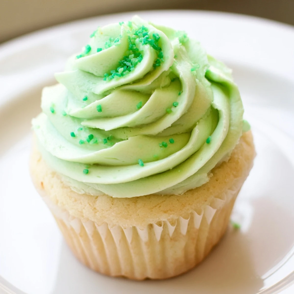 Freshly baked Shamrock Shake Cupcakes with minty green frosting and green sprinkles on a cooling rack.