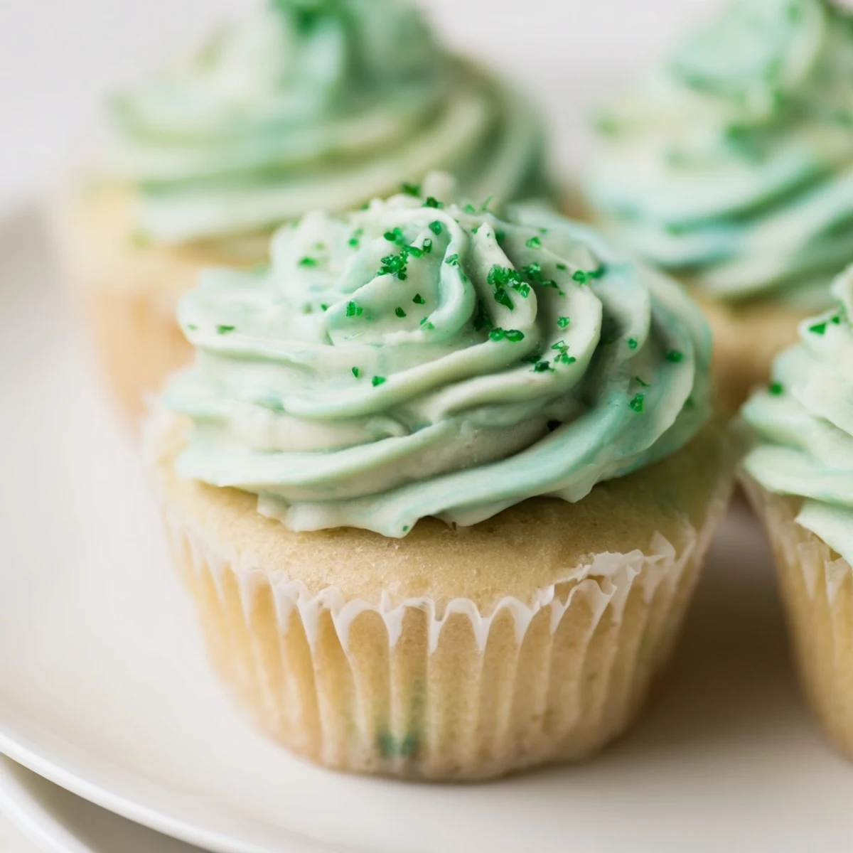 Frosted Shamrock Shake Cupcakes topped with creamy mint frosting and maraschino cherries for a festive treat.