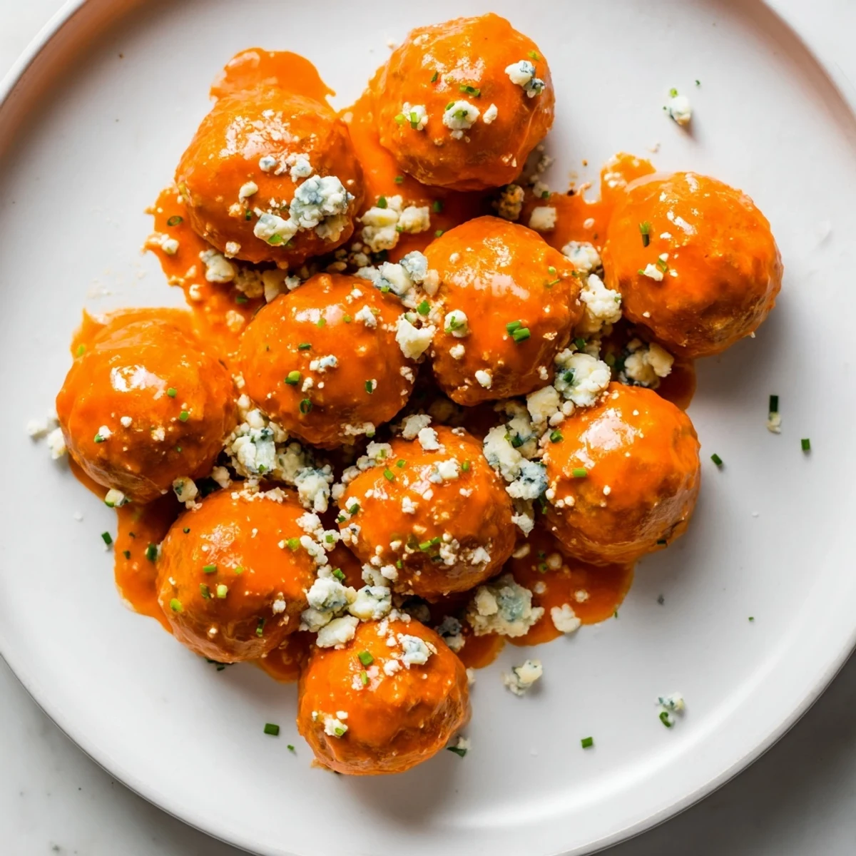 Buffalo chicken meatballs with blue cheese on a white plate, perfect for game day appetizers.