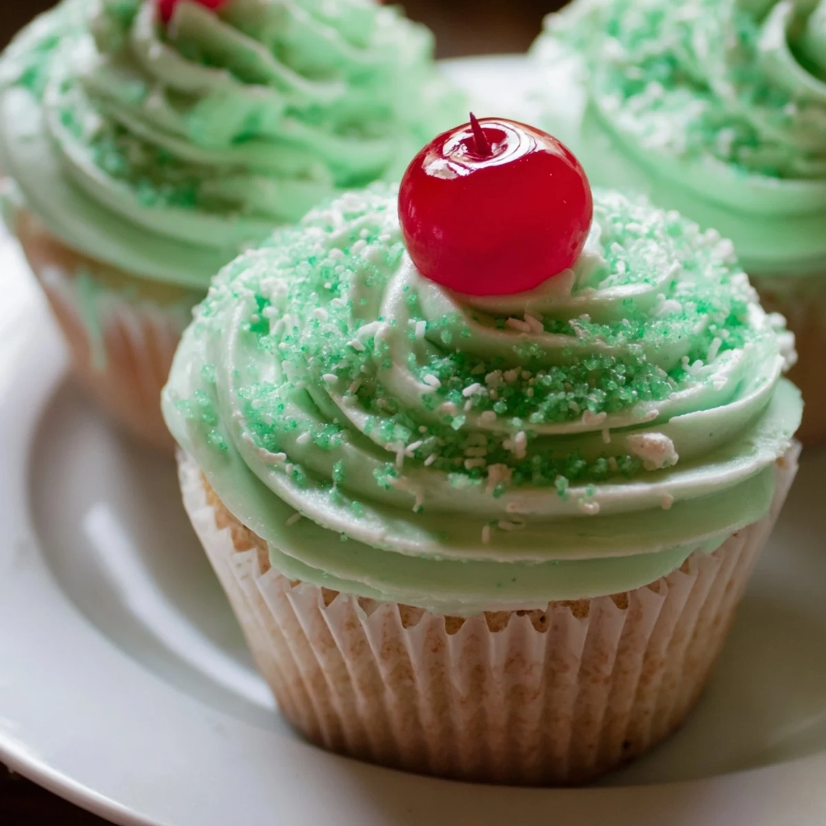 Twelve Shamrock Shake Cupcakes with mint frosting are lined up, showcasing vibrant green swirls and festive sprinkles for St. Patrick’s Day.  