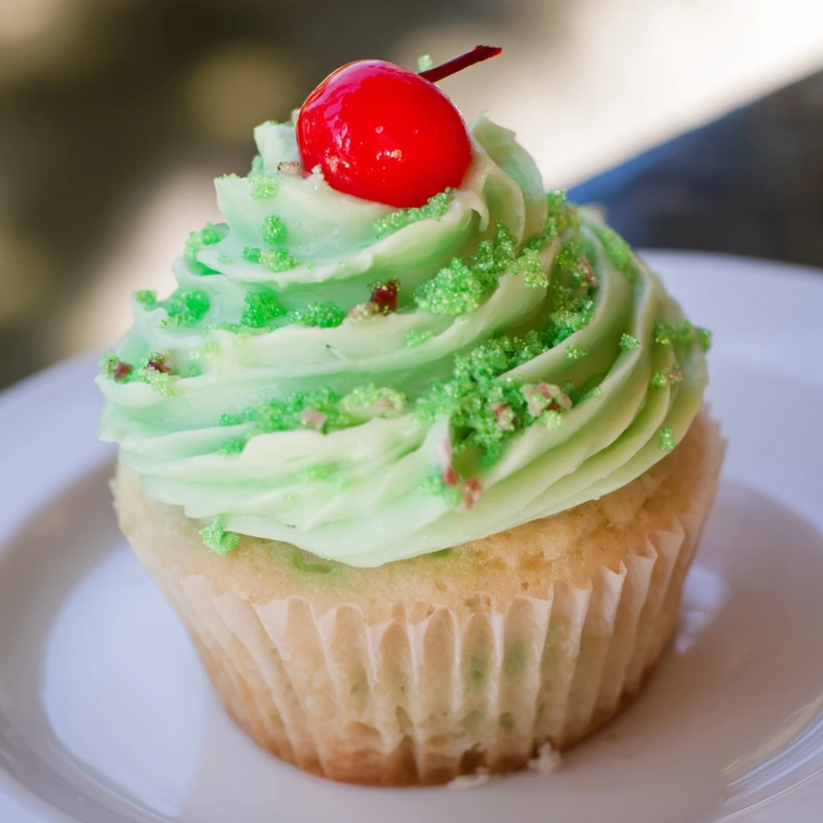 Freshly baked Shamrock Shake Cupcakes are stacked on a serving plate, their moist vanilla-mint crumb complemented by luscious green frosting.