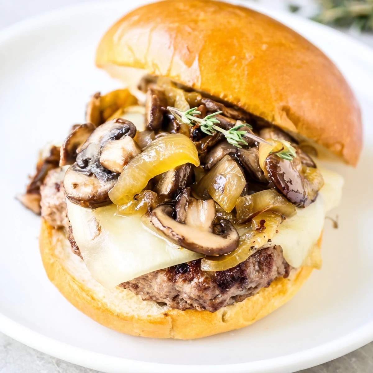 Sizzling Mushroom and Swiss Burger with Caramelized Onions sits on a plate, paired with golden french fries.
