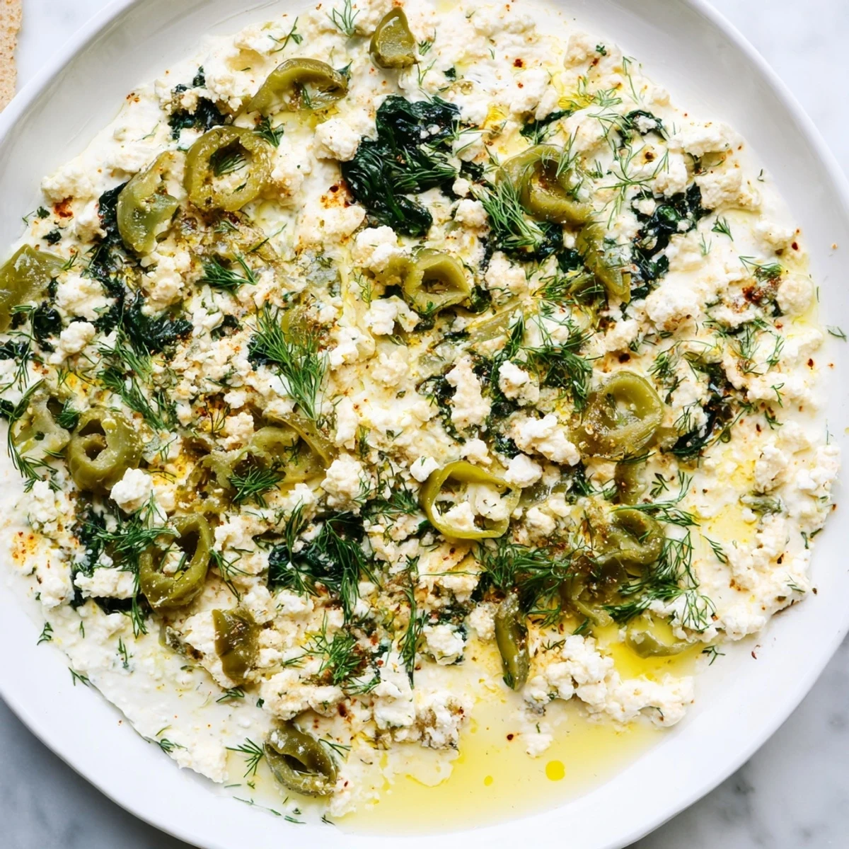 Creamy baked Spinach and Pepperoncini Baked Feta Dip, golden and bubbly in a dish, ready to serve with pita chips for a party.