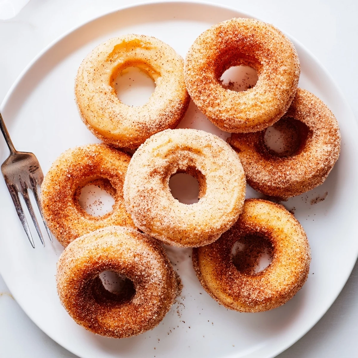 Twelve fluffy Delicious Baked Cinnamon Sugar Donuts You Cant Resist dusted with sweet cinnamon sugar for breakfast.