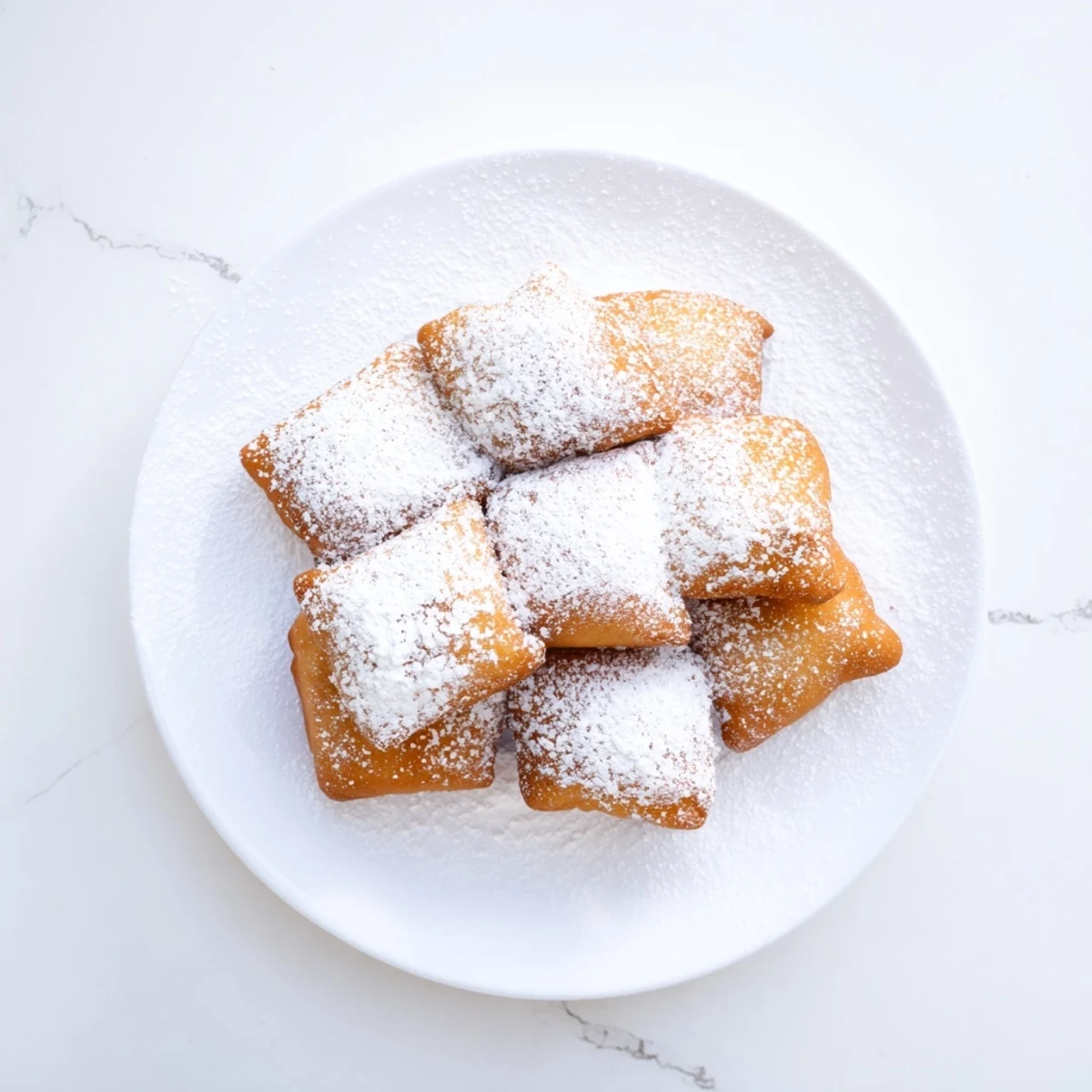 Pillowy Vanilla French Beignets piled high on a plate, ready to be enjoyed with coffee.