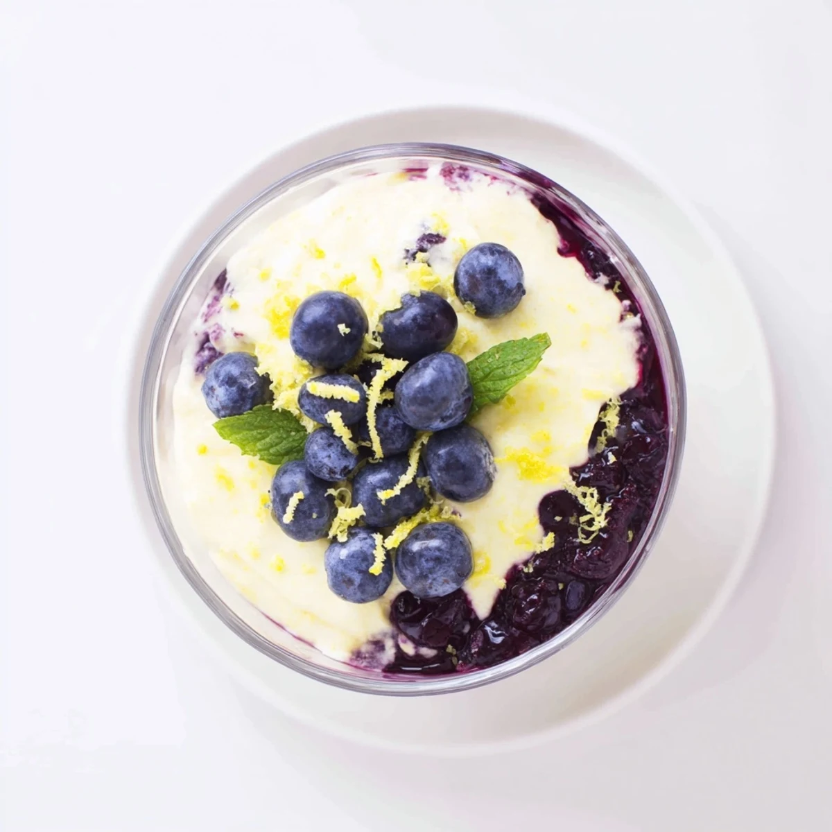 A close-up view of Lemon Blueberry Mousse topped with fresh berries and a sprig of mint.