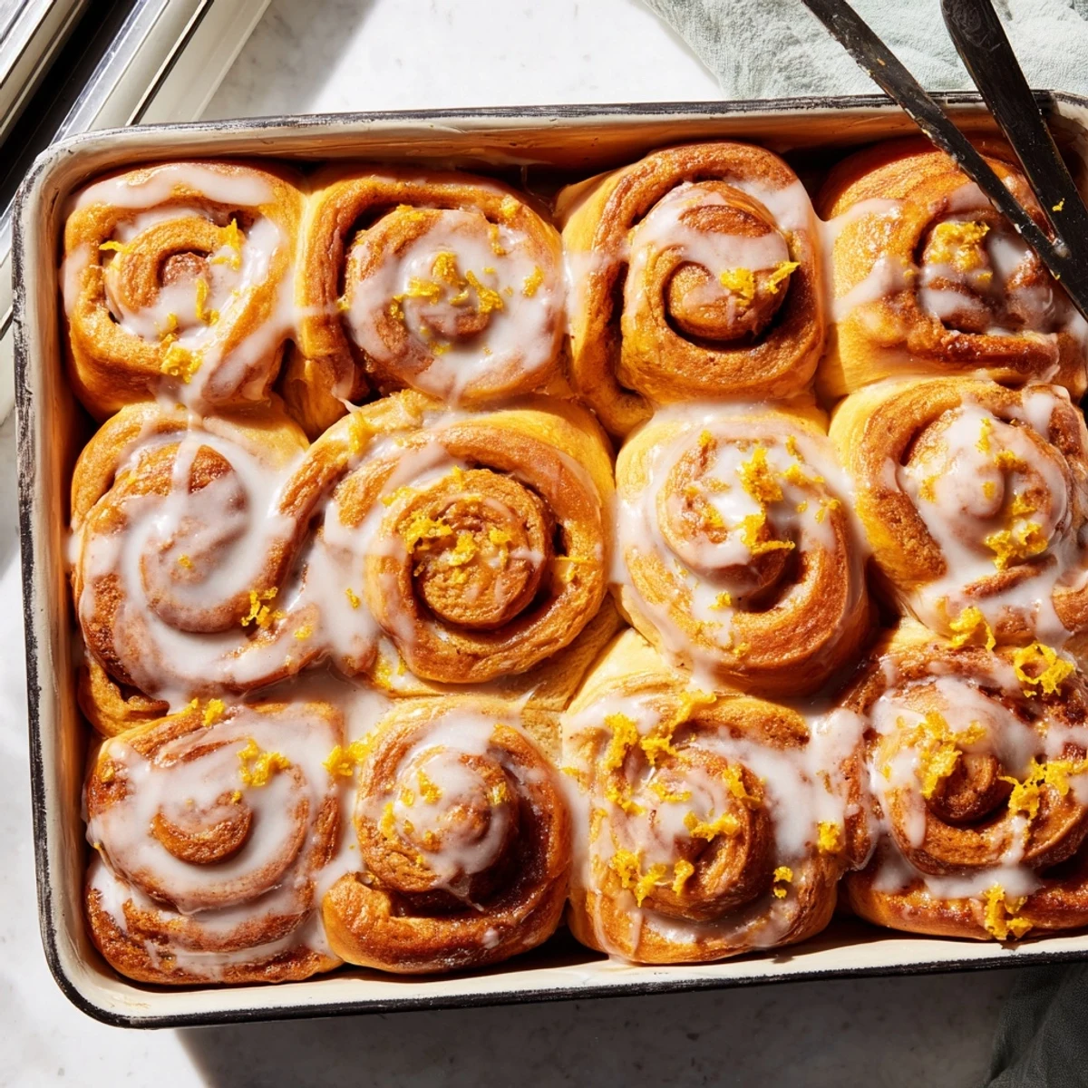 Warm Homemade Glazed Orange Rolls on a plate with a steaming cup of coffee.