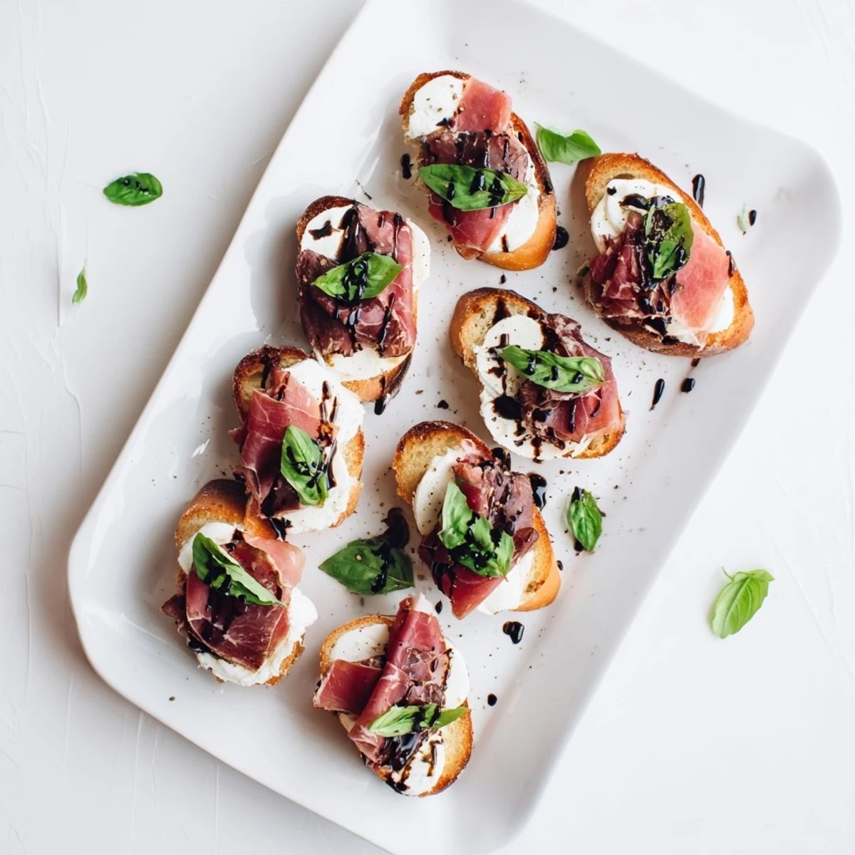 Fresh Mozzarella Beef Prosciutto Crostini garnished with torn basil and balsamic glaze, served ready to eat.