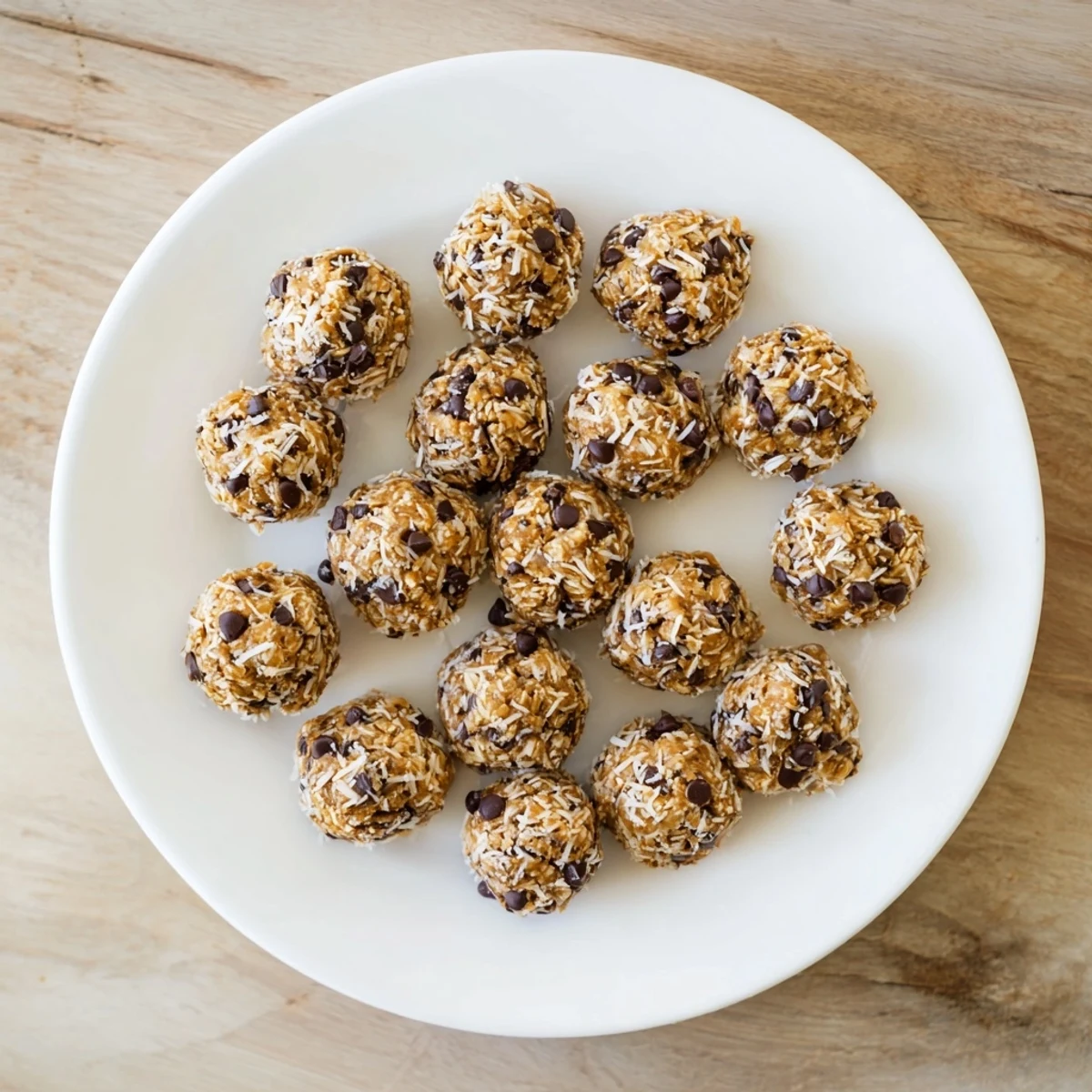 Hands holding a plate of golden brown Easy No Bake Chocolate Chip Energy Bites ready for a quick healthy snack.