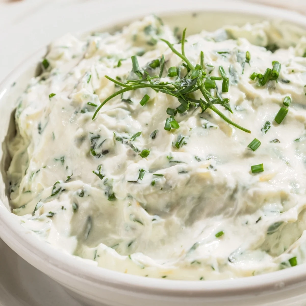 A bowl of Simple Easter Herb Cheese Dip garnished with fresh chives, dill, and radish slices for a spring appetizer.