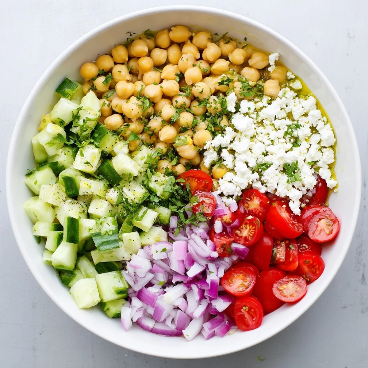 A protein-packed Chickpea Feta Avocado Salad is served with parsley and juicy cherry tomatoes on a white plate.
