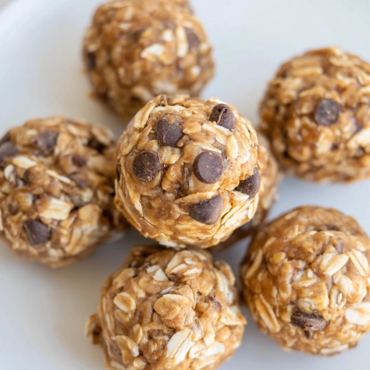 Chewy No Bake Peanut Butter Energy Bites served in a glass jar with a rustic wooden spoon.