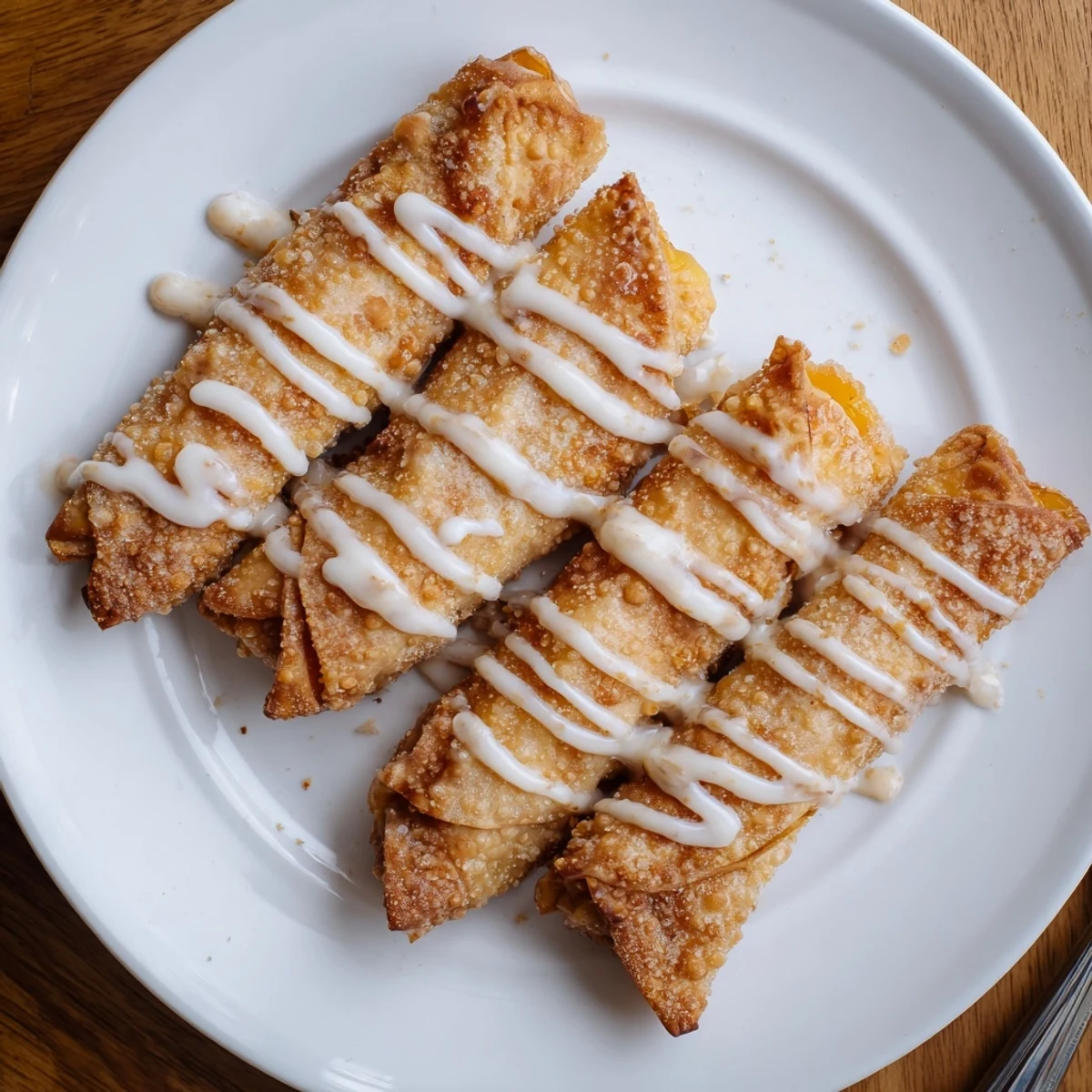 Freshly fried Peach Cobbler Egg rolls are served warm beside a scoop of vanilla ice cream.