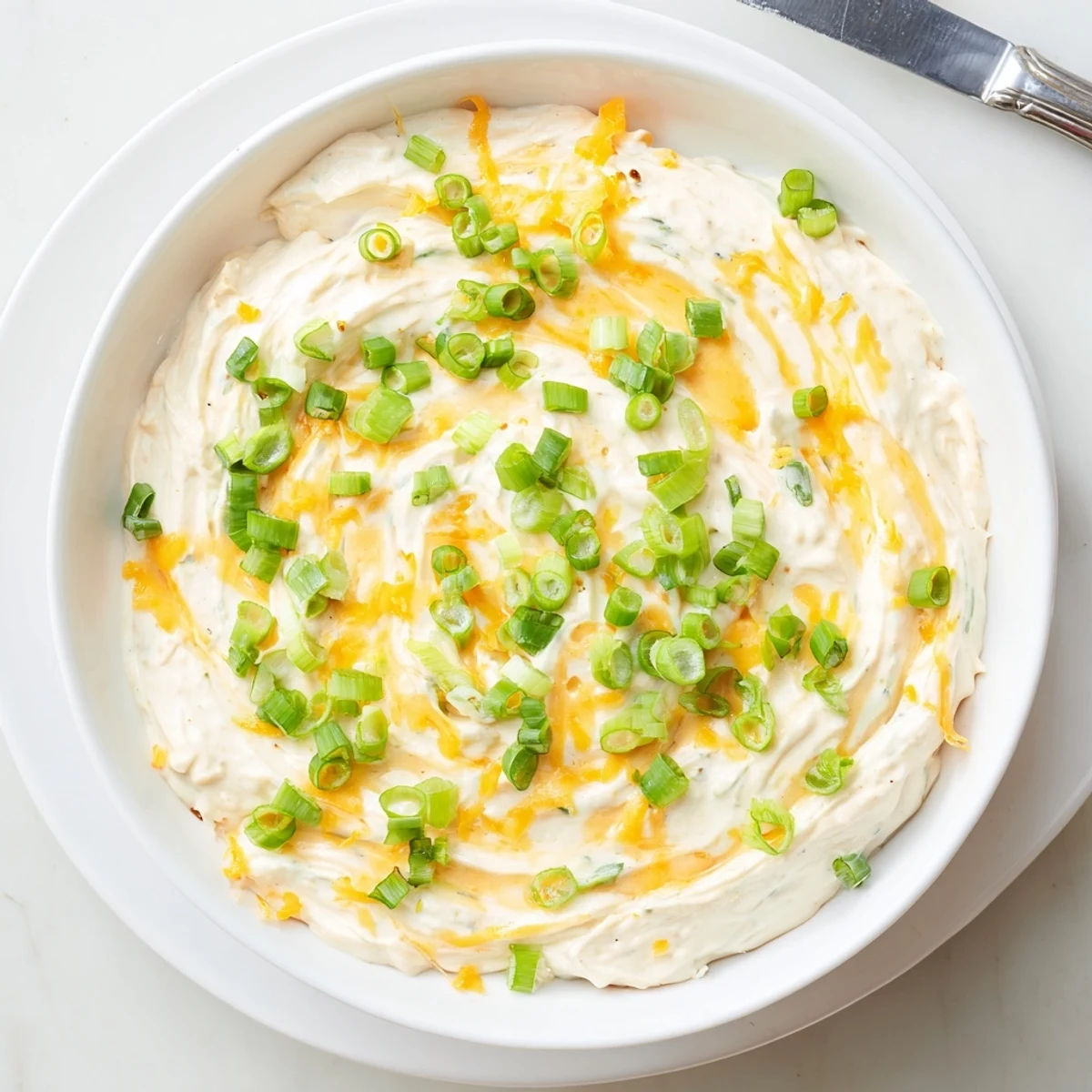 Smooth cheese appetizer dip sprinkled with green onions, perfect for party pretzel platters