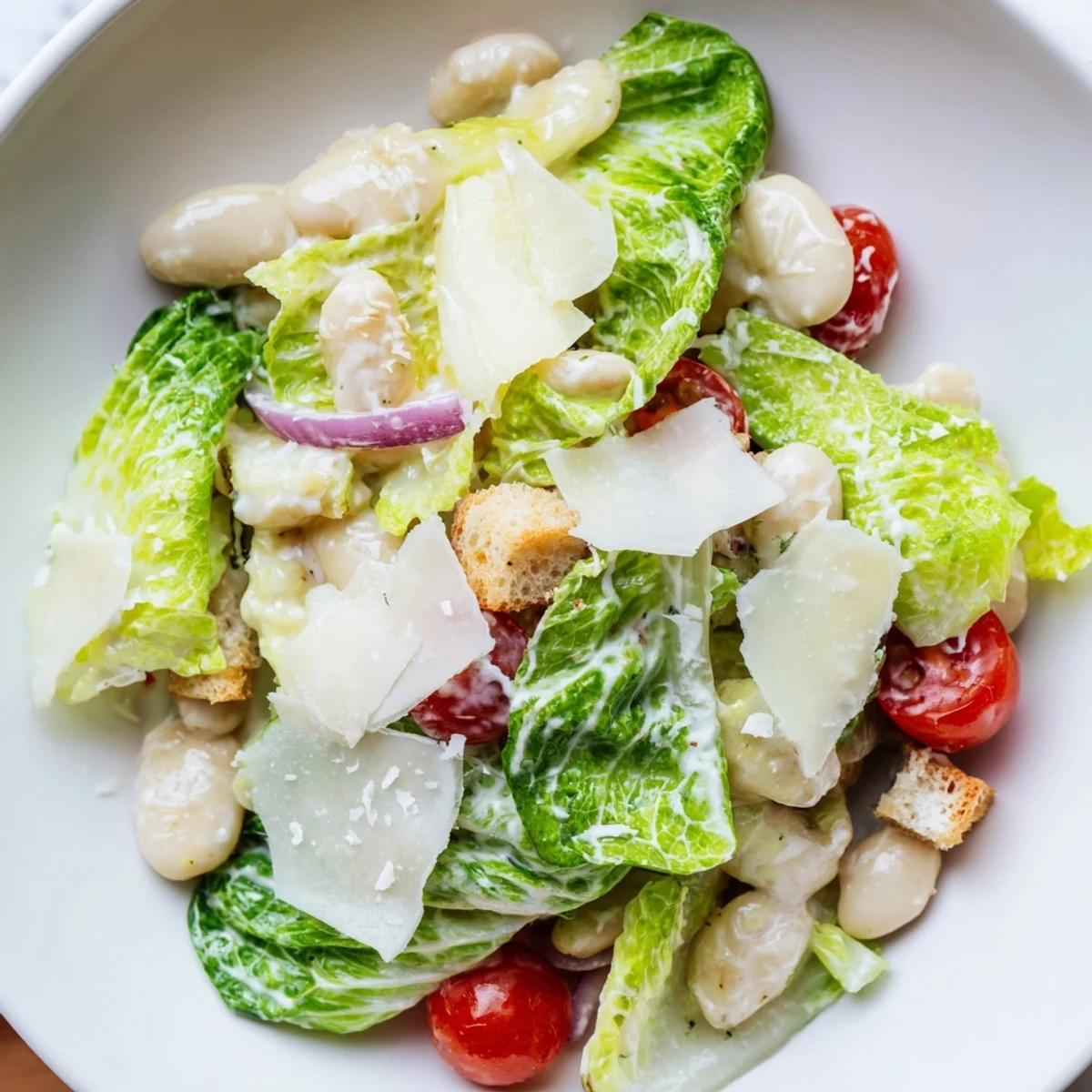 Vegetarian butter bean Caesar salad tossed in zesty dressing topped with shaved Parmesan cheese and crispy croutons
