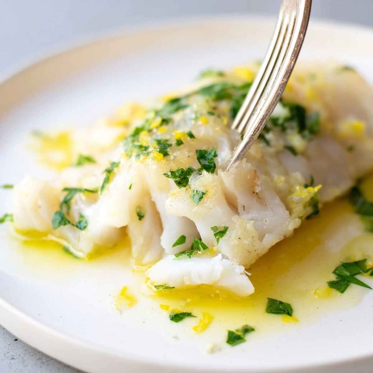 Healthy lemon garlic baked cod served with fresh herbs and extra lemon wedges for garnish