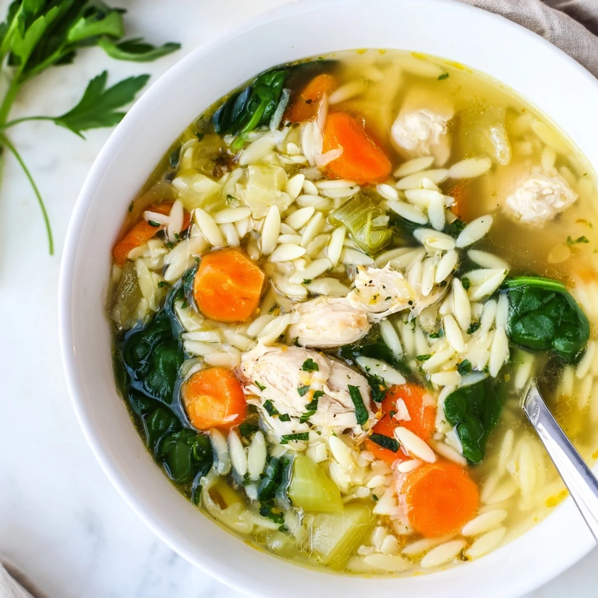 Steaming spring lemon chicken orzo soup with carrots, celery, and tender chicken swimming in a zesty, aromatic broth