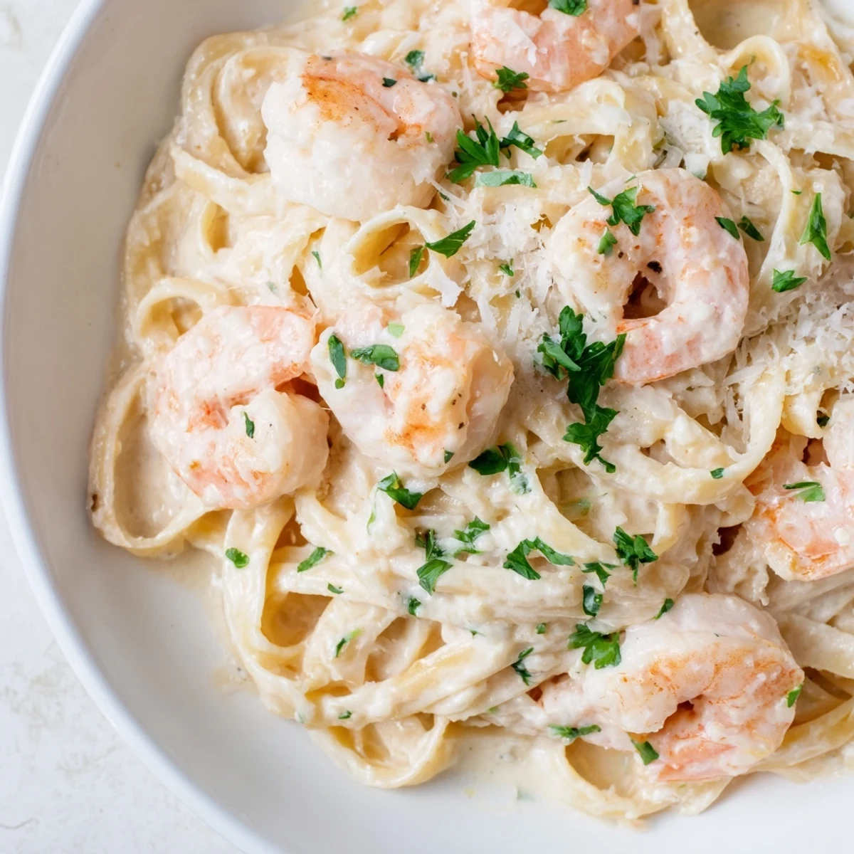 Close-up of creamy shrimp fettuccine pasta with homemade Alfredo sauce draping over noodles and plump seared shrimp