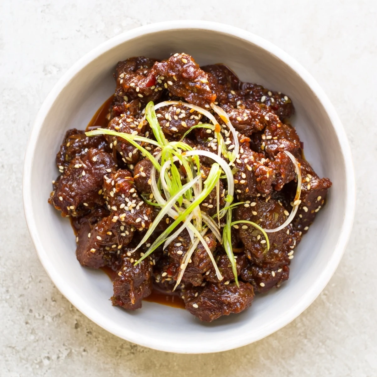 Slow cooker Korean beef served fluffy white steamed rice with vibrant sliced scallions and toasted sesame topping