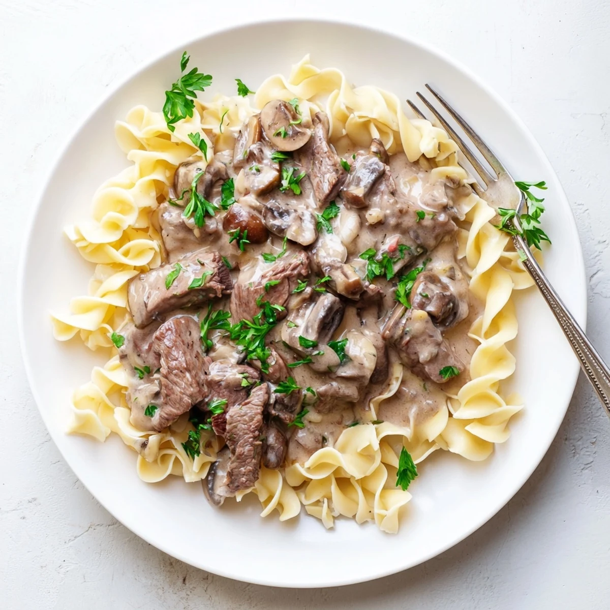 Creamy beef stroganoff with tender beef strips in rich mushroom sauce served over egg noodles