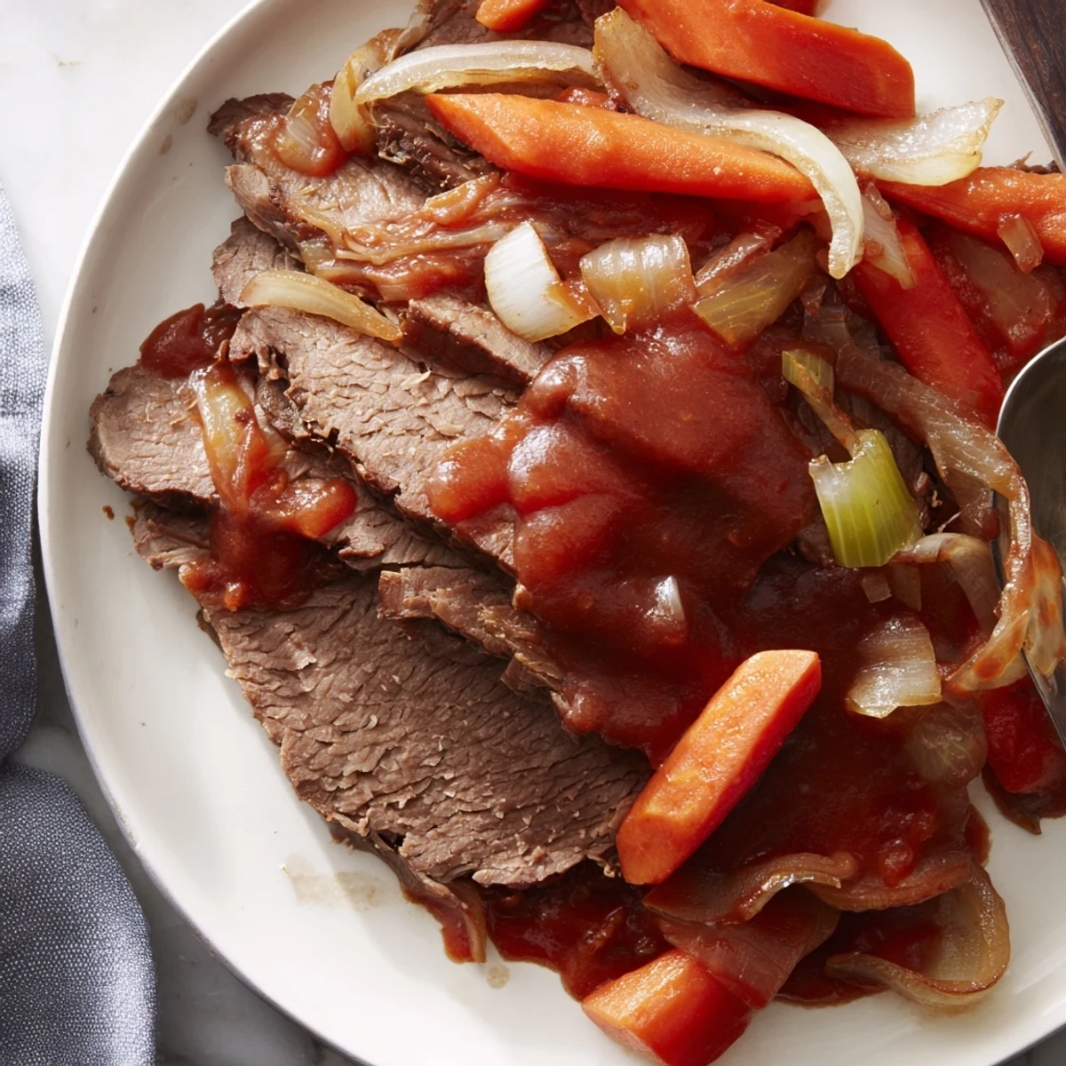 Slow cooker beef brisket with tender sliced meat nestled beside caramelized onions and carrots in rich savory sauce