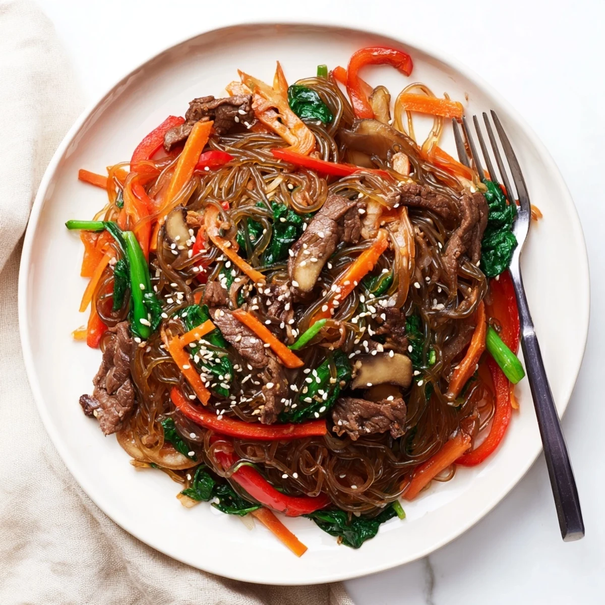 Chewy sweet potato noodles tossed with marinated beef strips and crisp bell peppers in savory gochujang glaze