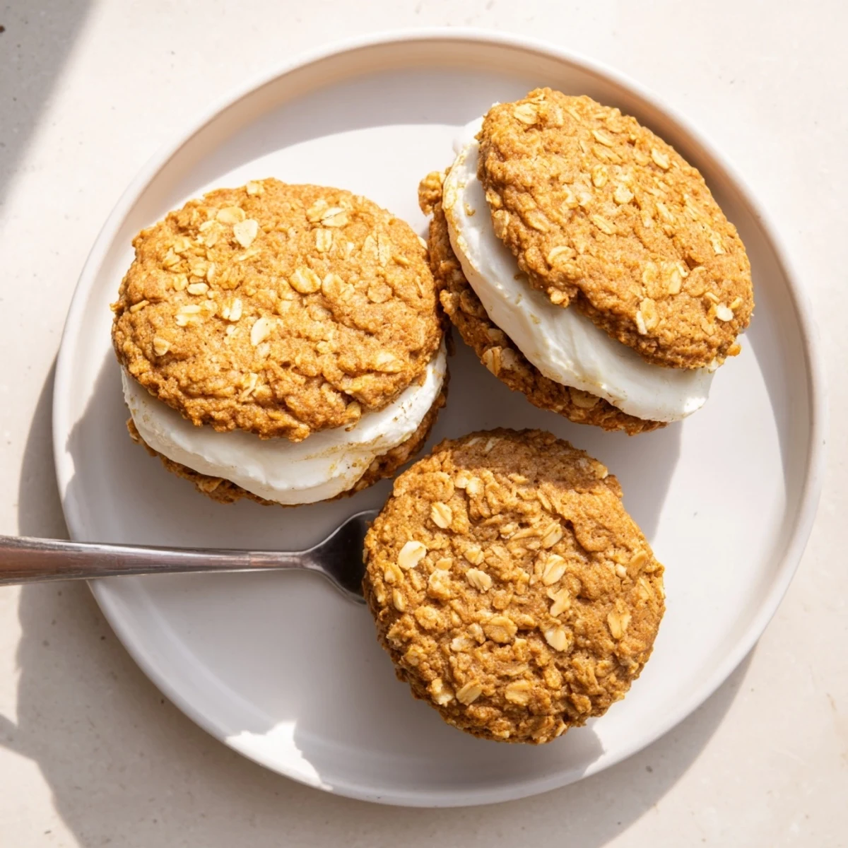 Stack of nostalgic oatmeal cream pies showing golden brown cookie edges and fluffy white frosting