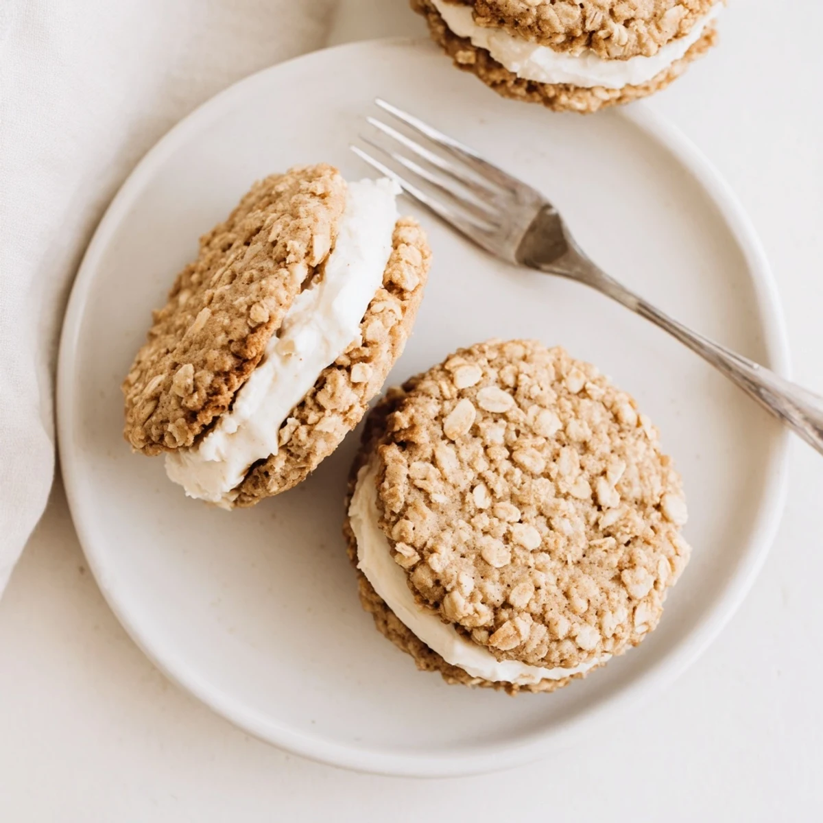 Close-up of chewy oatmeal cookies sandwiching sweet cream filling with oats visible throughout