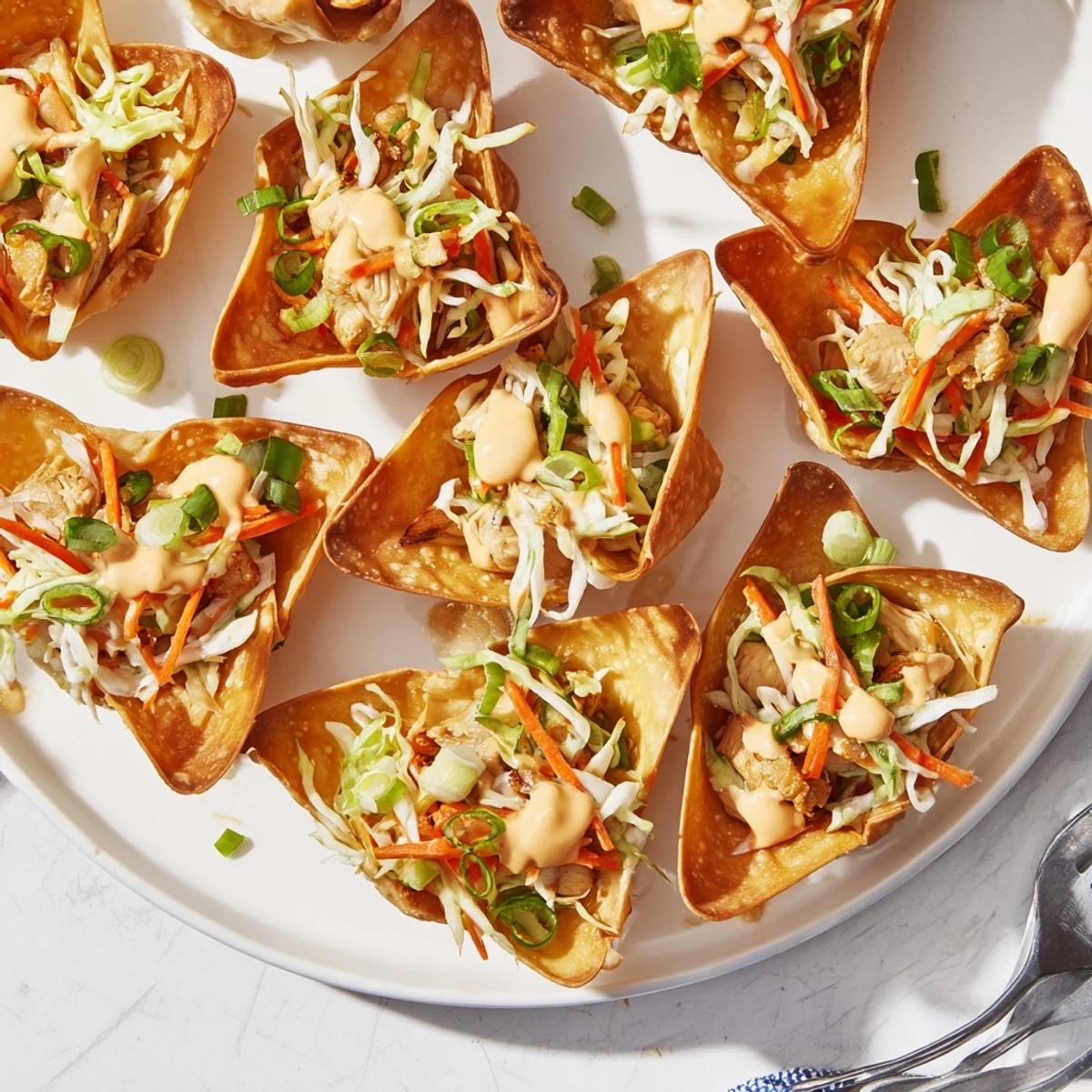 Golden crispy chicken wonton tacos topped with colorful vegetable slaw and zesty Asian sauce