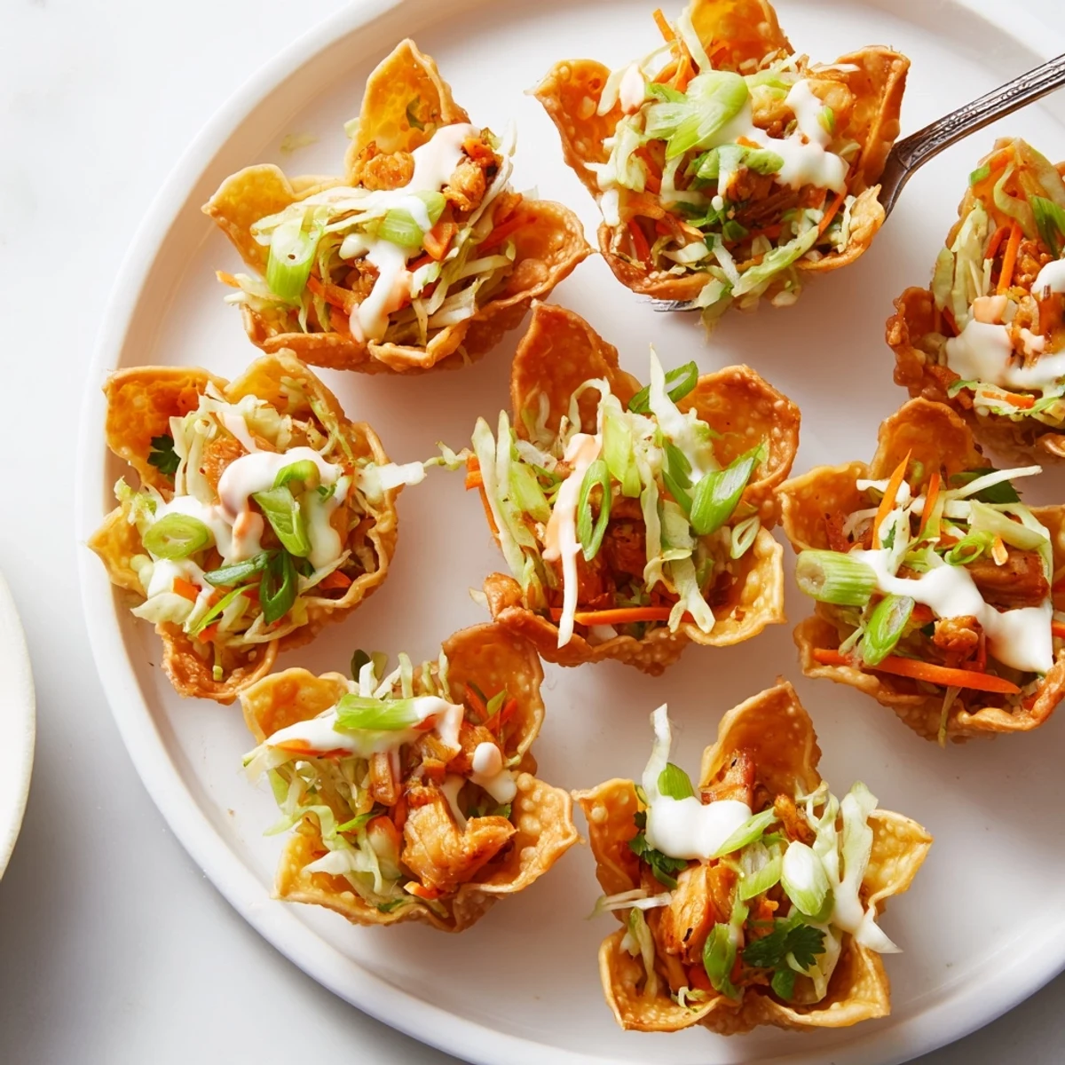 Baked golden wonton tacos loaded with seasoned chicken fresh cilantro slaw and creamy chili sauce